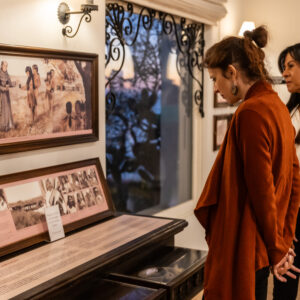 Guests reading museum displays about Native Americans at Casa Romantica at sunset