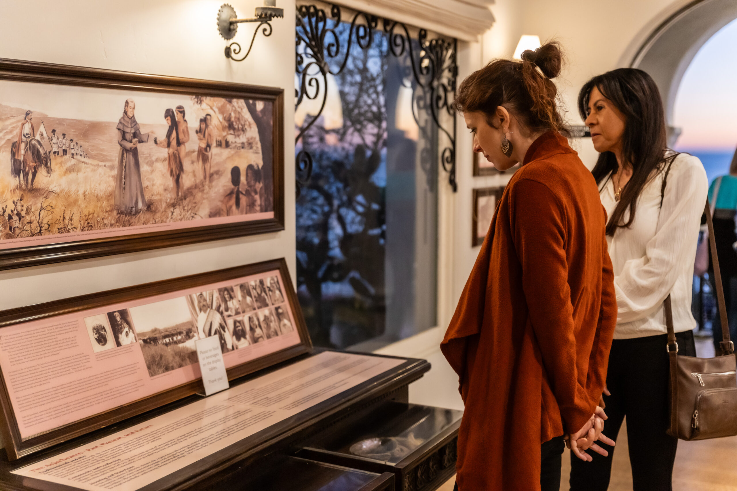 Guests reading museum displays about Native Americans at Casa Romantica at sunset